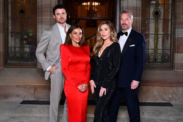 group of four individuals dressed in formal attire standing together at an upscale venue