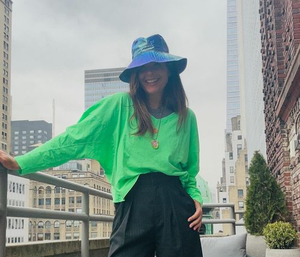 a person wearing a hat and standing on a balcony