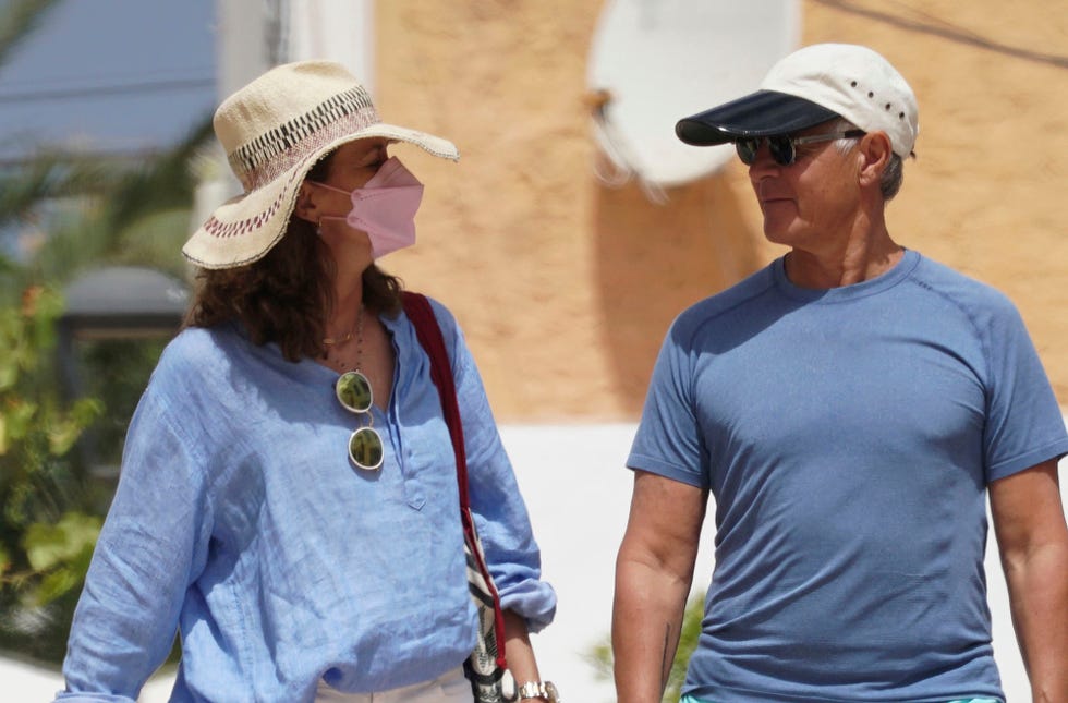 la empresaria, con sombrero y mascarilla, charla con el financiero