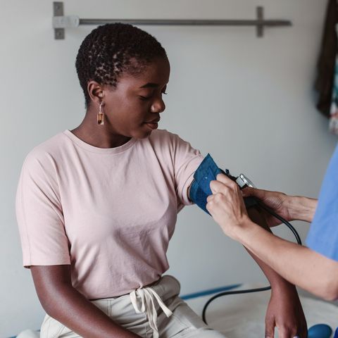 nurse checking blood pressure of female patient in clinic