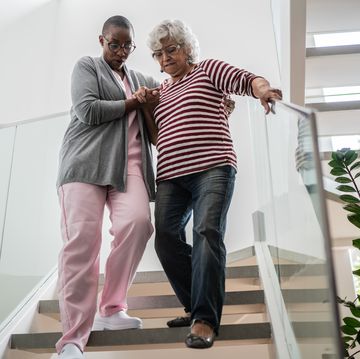nurse helping a senior woman walking the stairs