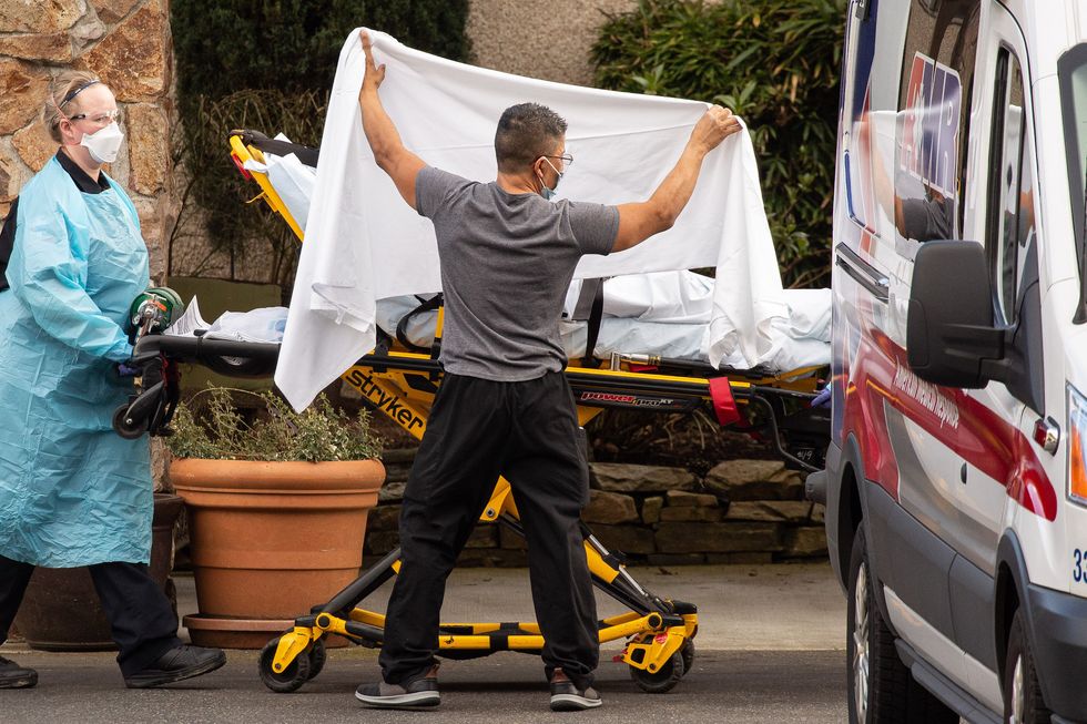 seattle, wa   february 29 healthcare workers transport a patient on a stretcher into an ambulance at life care center of kirkland on february 29, 2020 in kirkland, washington dozens of staff and residents at life care center of kirkland are reportedly exhibiting coronavirus like symptoms, with two confirmed cases of covid 19 associated with the nursing facility reported so far photo by david rydergetty images