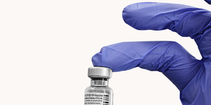 gloved hands holding a vial of covid 19 vaccine