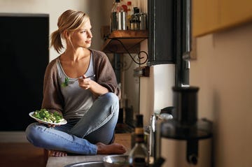 una mujer come alimentos ricos en vitamina d sentada en su cocina