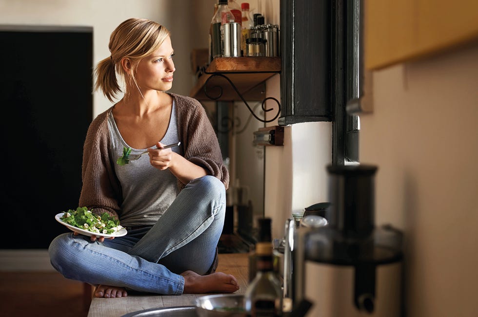 una mujer come alimentos ricos en vitamina d sentada en su cocina