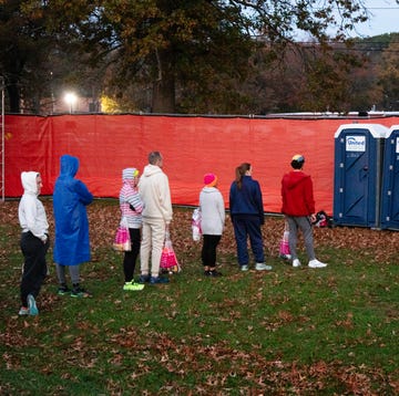 a group of people standing in line for a porta potty a group of people standing in line for a porta potty