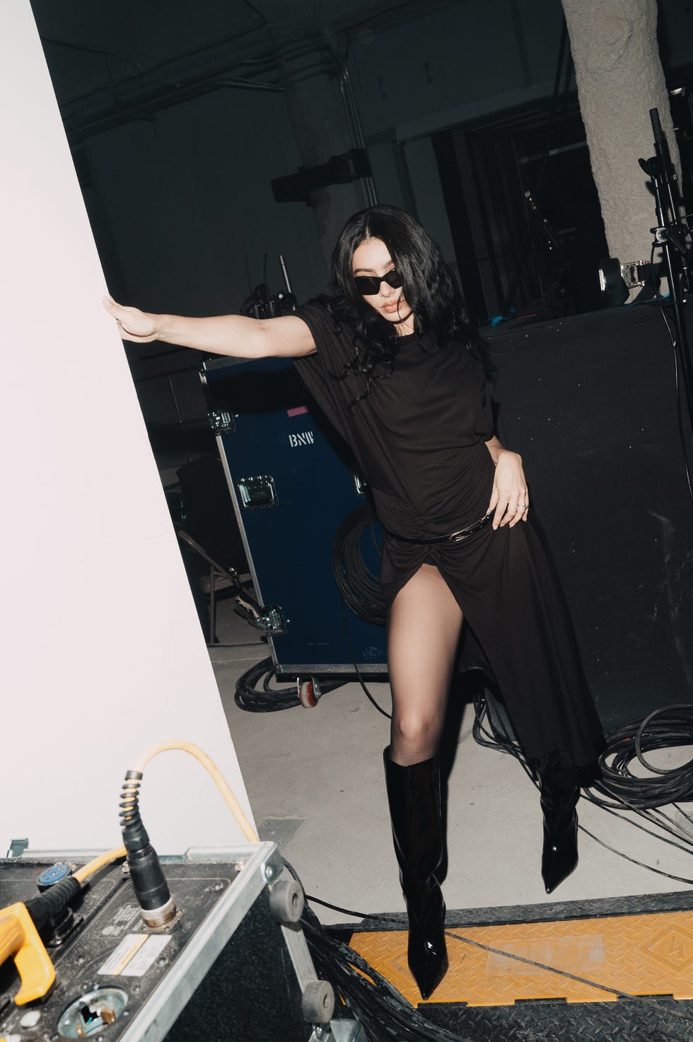 person wearing a stylish outfit posing in a backstage setting