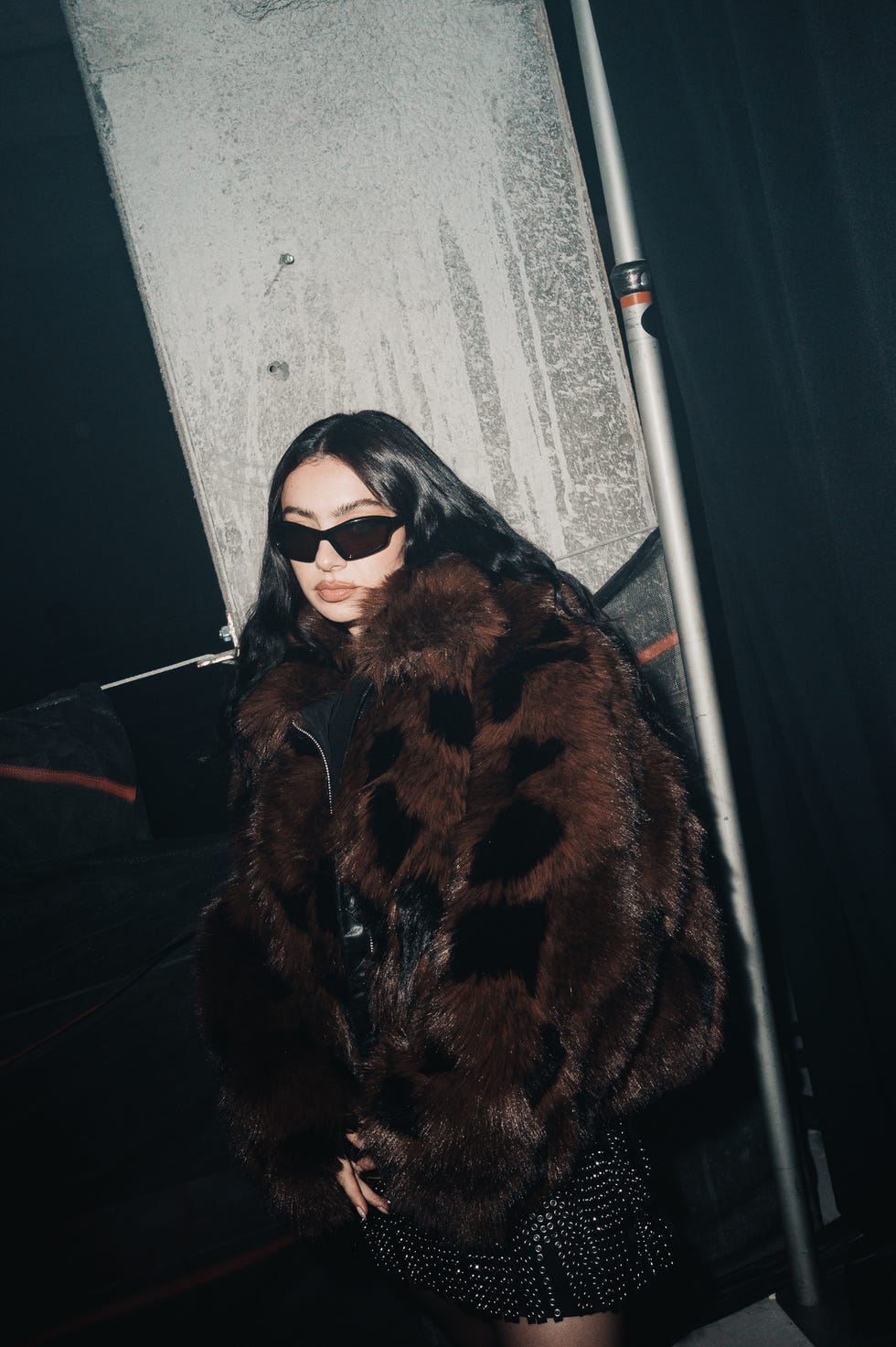 a person wearing a fur coat and skirt against a dark background