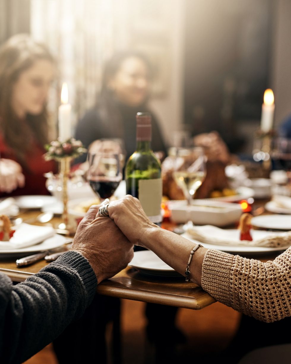 shot of family holding hands in prayer before having a christmas lunch together
