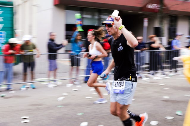 a runner participating in a race grabbing a cup of water from a hydration station