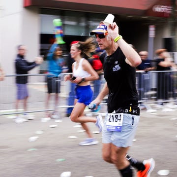 a runner participating in a race grabbing a cup of water from a hydration station a runner participating in a race grabbing a cup of water from a hydration station