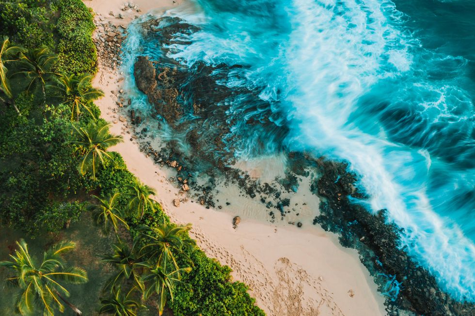 oahu, drone photography of beach, surf and water and lush green landscape leading up to it