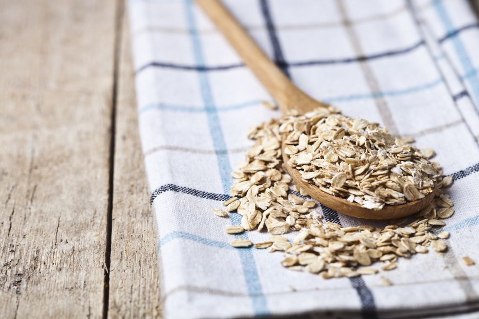 oat flakes in wooden spoon on linen napkin,golden wheat ears