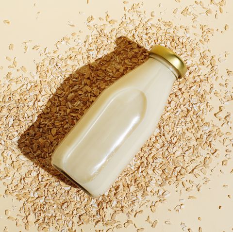 oat milk in glass bottle and oatmeal flakes on beige background healthy vegan non dairy organic drink with flakes lactose free milks in minimal flat lay style top view