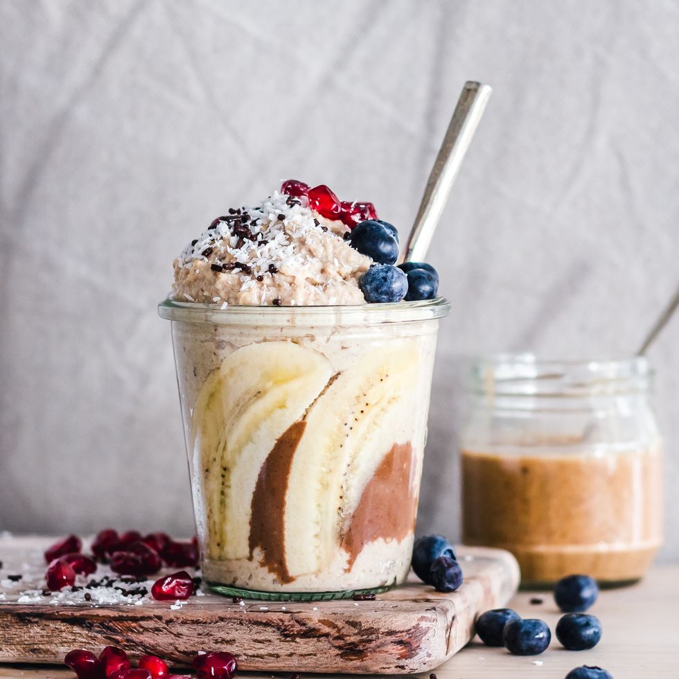 overnight oats with banana, peanut butter, blueberries and pomegranate for good housekeeping's best high calorie snacks