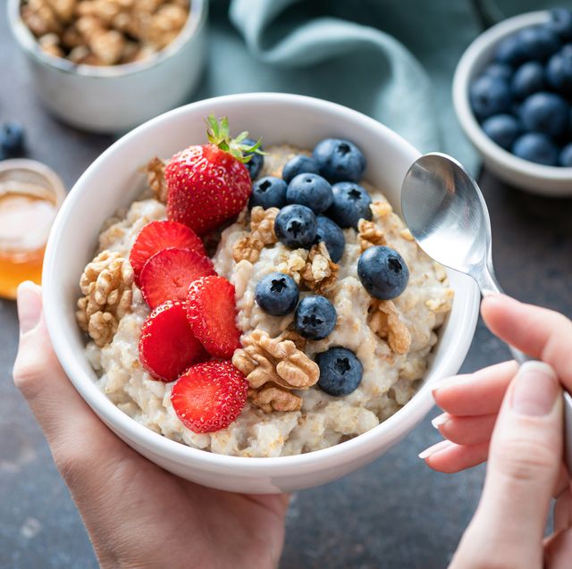 oatmeal porridge bowl with berry fruits in female hands