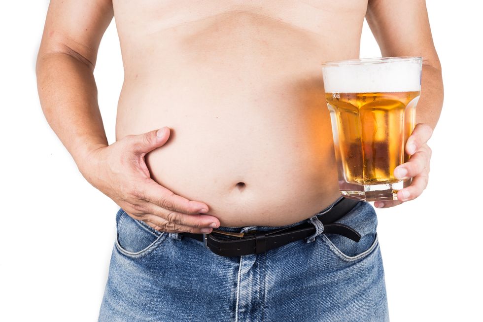 Obese man with big belly holding a glass of beer