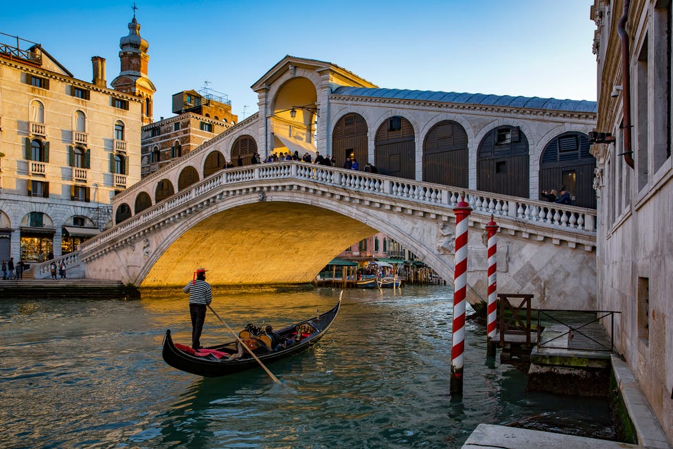 a person rowing a boat under rialto bridge