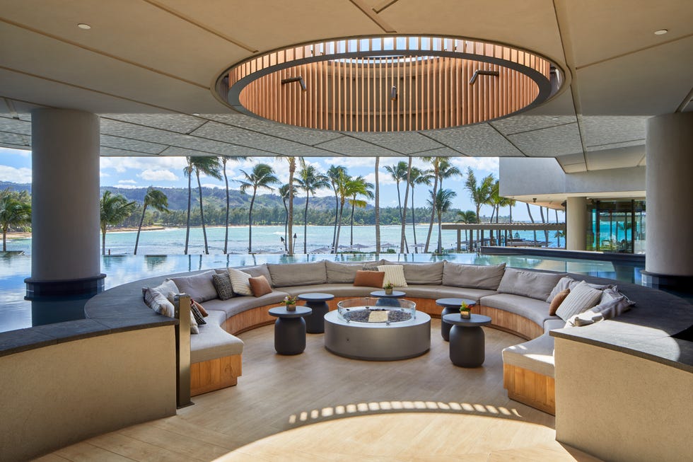 round seating area with overhead light and palm trees and ocean in the back