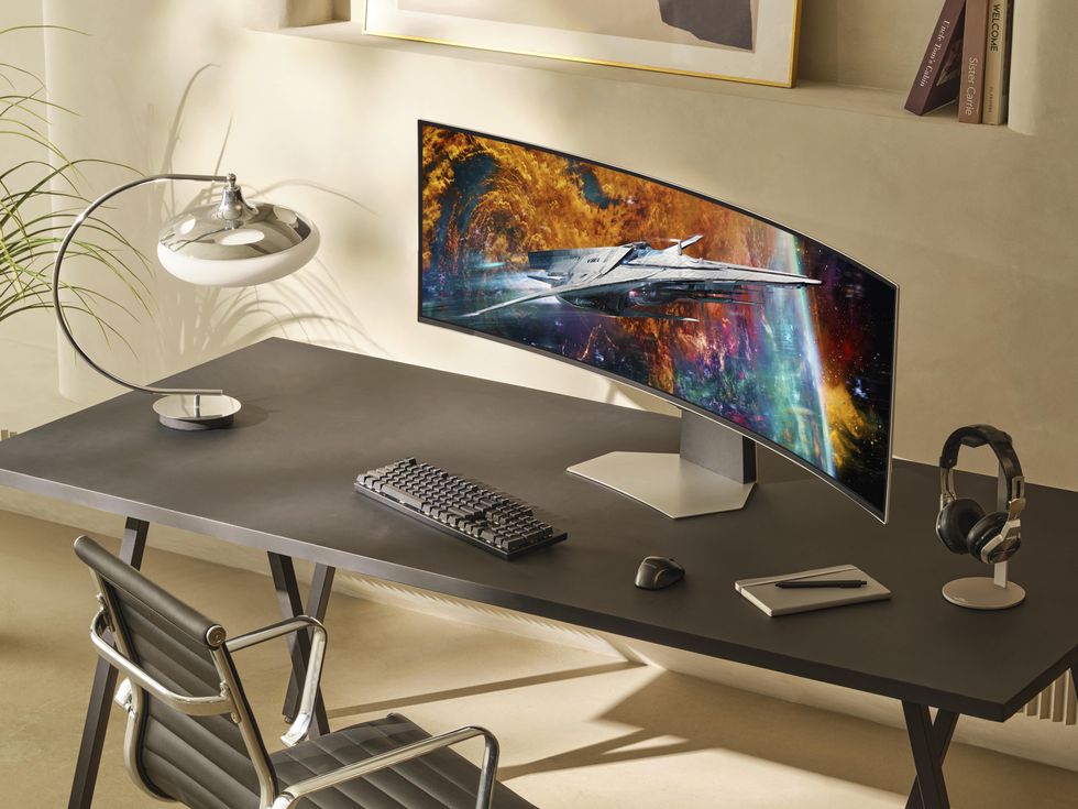 un escritorio con una computadora y una silla y un monitor de juegos samsung con pantalla curva