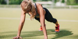 blond haired woman doing pushup or press up on a sports field