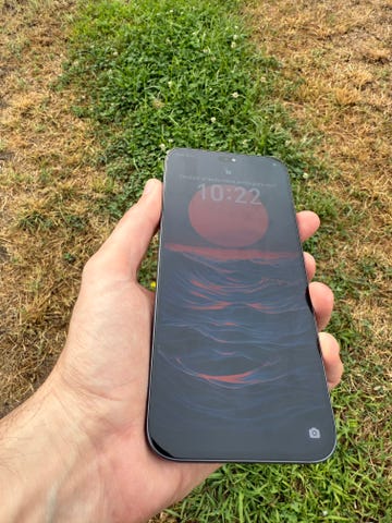 una mano sujeta un teléfono móvil honor 400 lite cuya pantalla muestra un dibujo de un anochecer en el mar