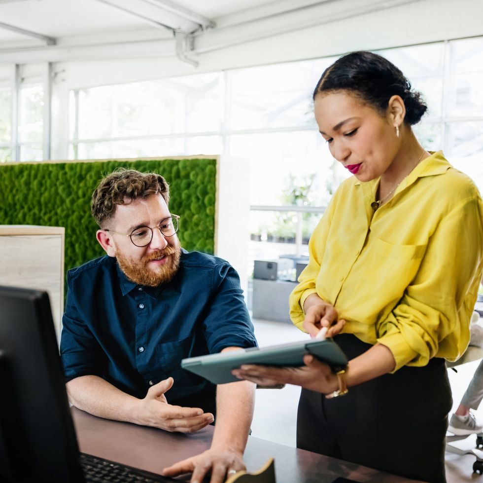 office manager showing documents on digital tablet to colleague