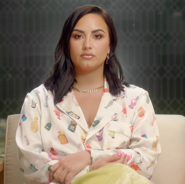demi lovato in a patterned white pajama top and silver necklace, looking straight into the camera during her youtube documentary dancing with the devil