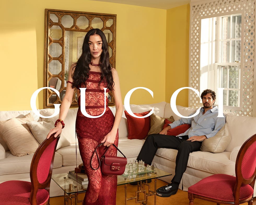 a fashion advertisement featuring a woman in a red dress and a man sitting on a couch