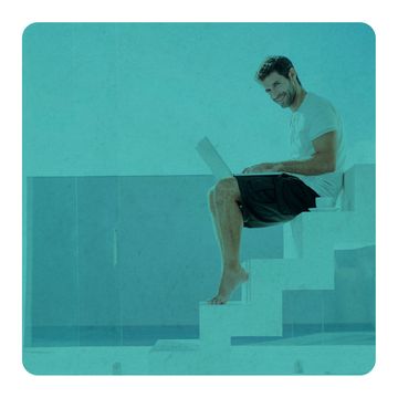un hombre teclea en un ordenador portátil sentado en unas escaleras