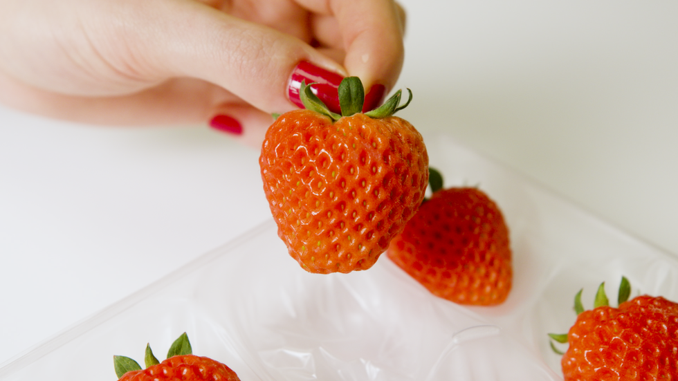 a hand holding a strawberry
