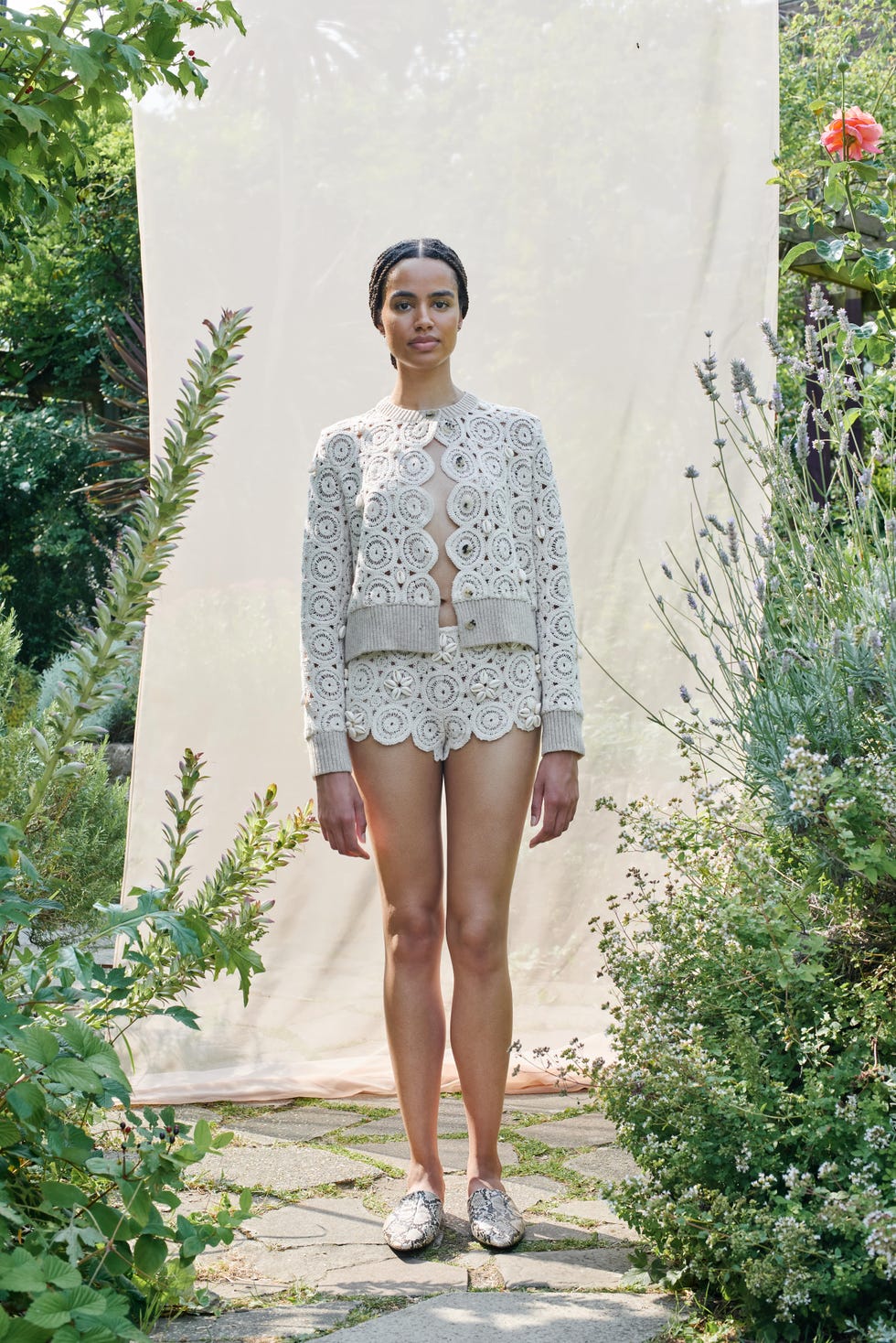 model wearing crochet outfit standing in a garden setting