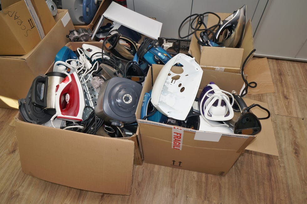 a huge lot of the old used and broken spare parts from no name mass production electric home applances devices lies on a cardboard boxes. plastics and metals will be sent for recycling.