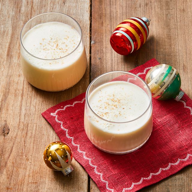 two glasses of old fashioned eggnog with christmas ornaments on the side