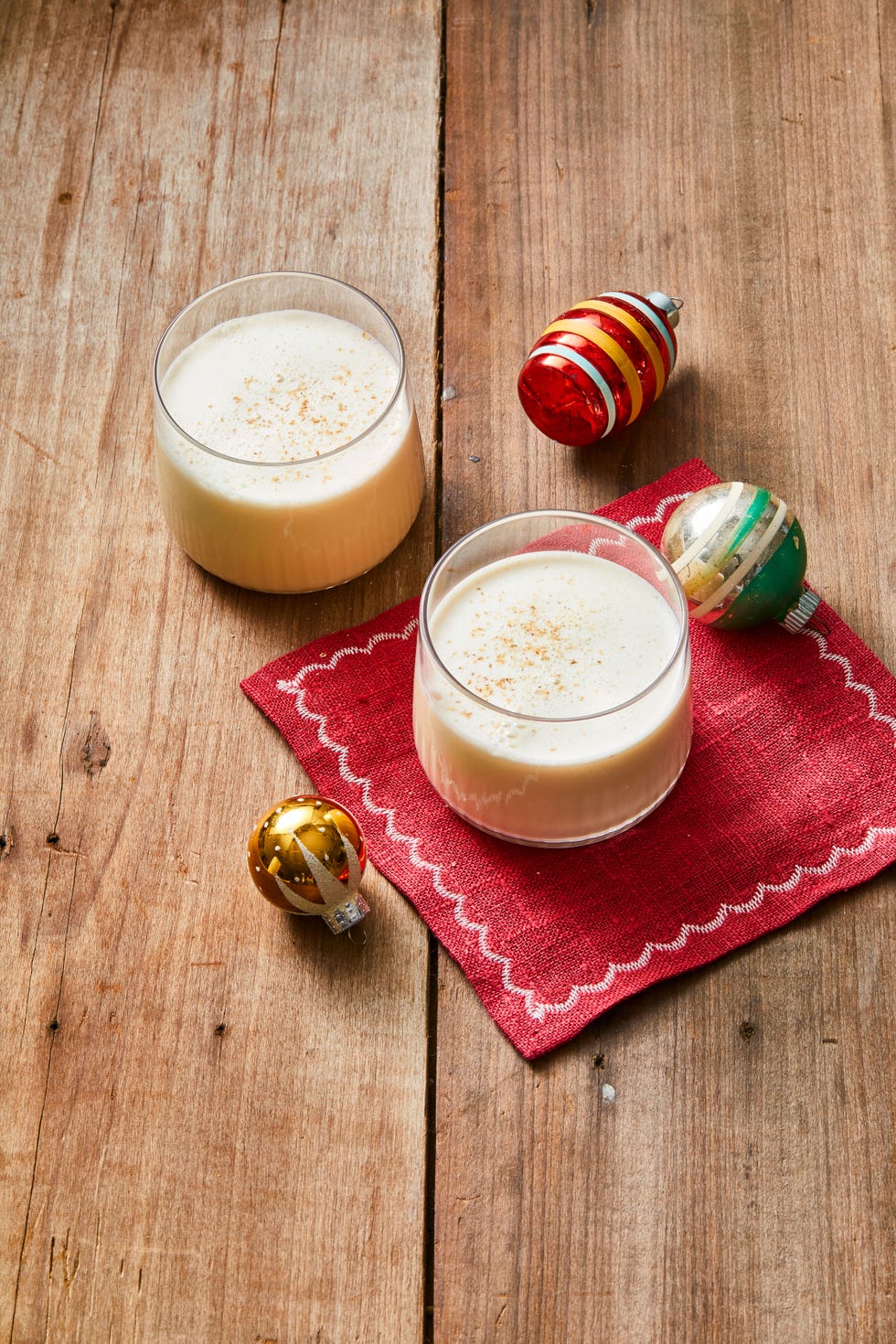 eggnog in two glasses with ornaments on the side