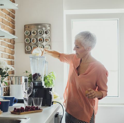 older caucasian woman making smoothie in kitchen