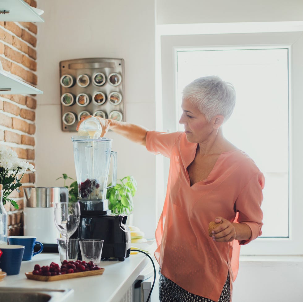 older caucasian woman making smoothie in kitchen