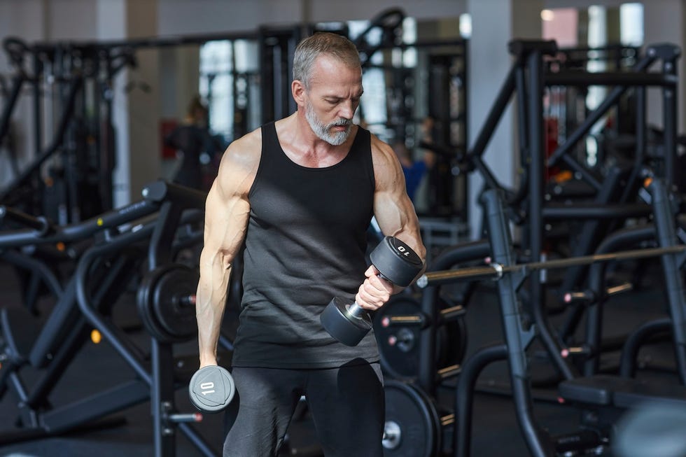 strong mature man doing exercise with dumbbells in gym strong mature man doing exercise with dumbbells in gym