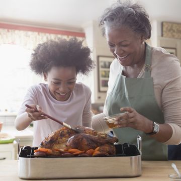 thanksgiving traditions   older woman and granddaughter cooking together in kitchen