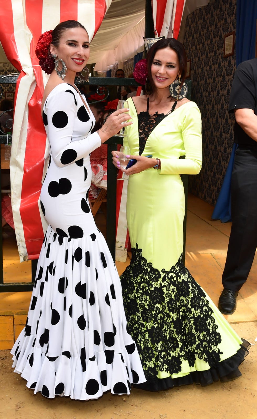 las hermanas moreno, vestidas de flamenca, brindan frente a una caseta