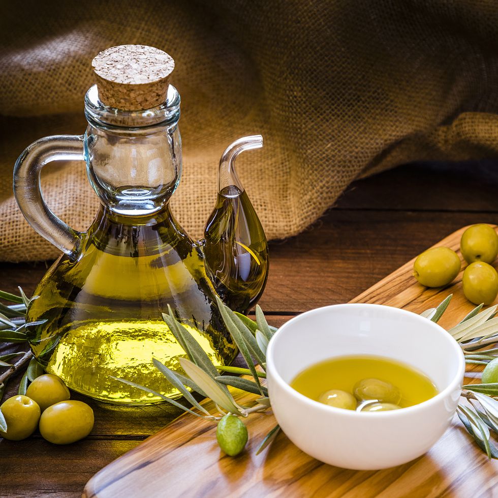 olive oil bottle with olive branch on a olive wooden cutting board with copy space