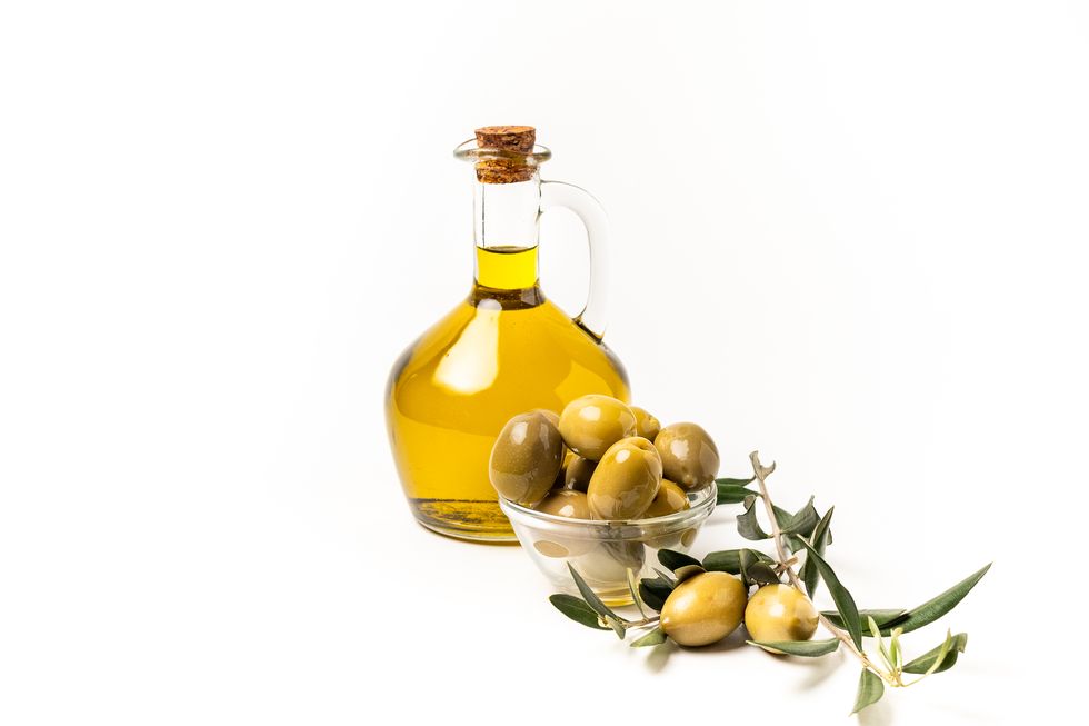olive oil in a bottle, green olives and olive tree branches isolated on white background