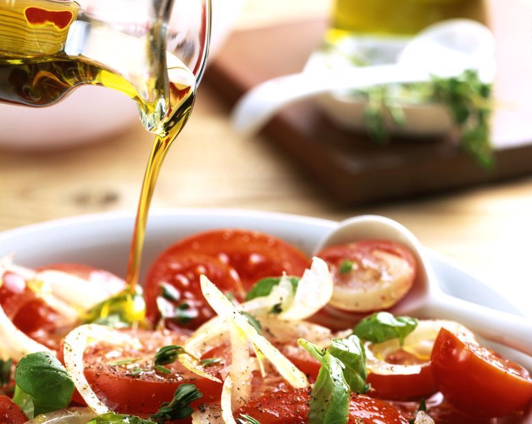 olive oil pouring over tomato and basil salad