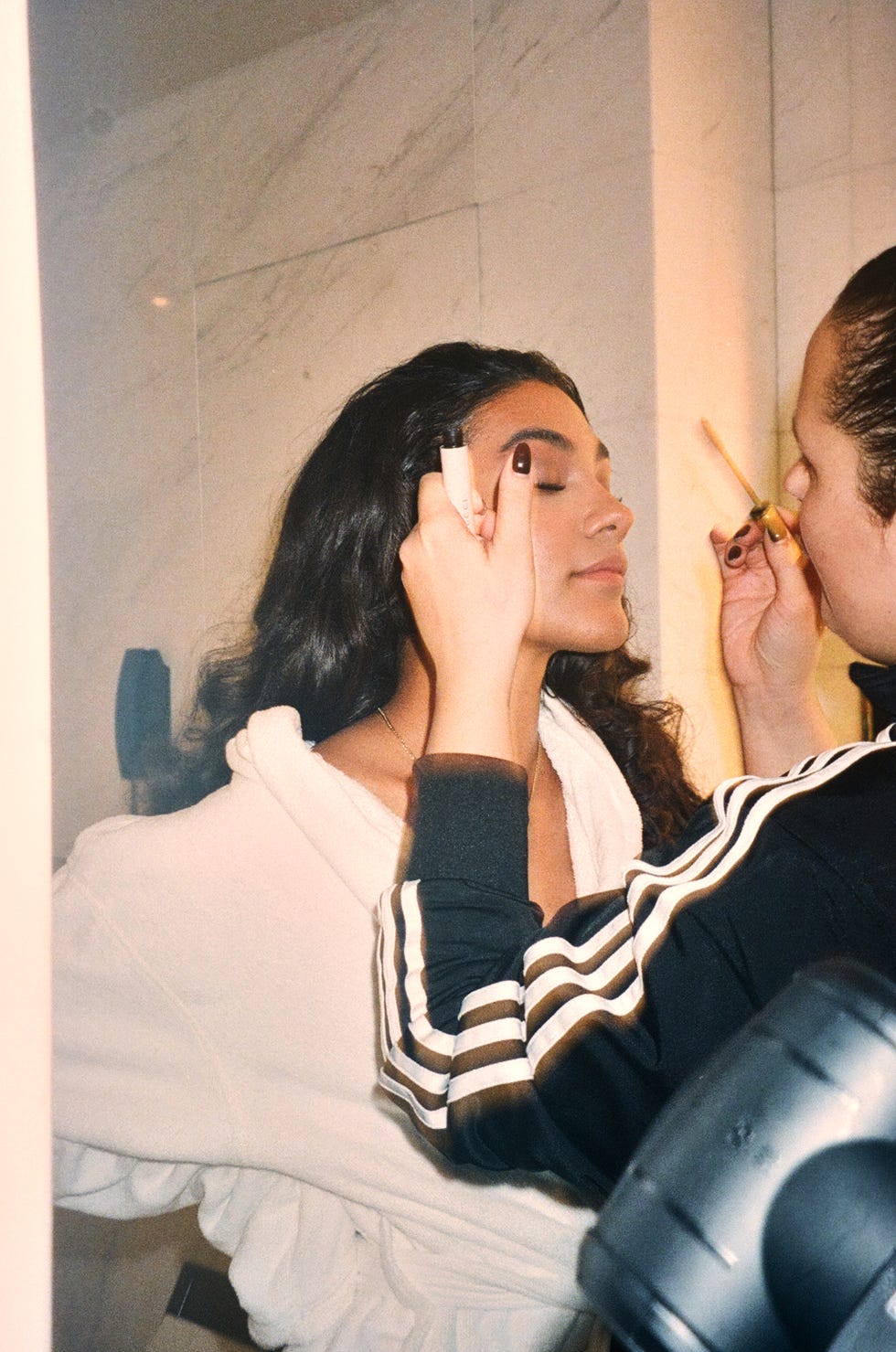 two individuals engaged in a hair styling process in a bathroom setting