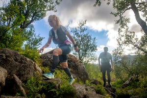 vrouw trailrun heuvel op in groene omgeving