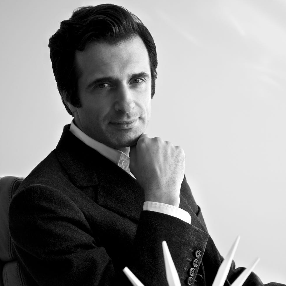 a person dressed in formal attire seated with a thoughtful expression