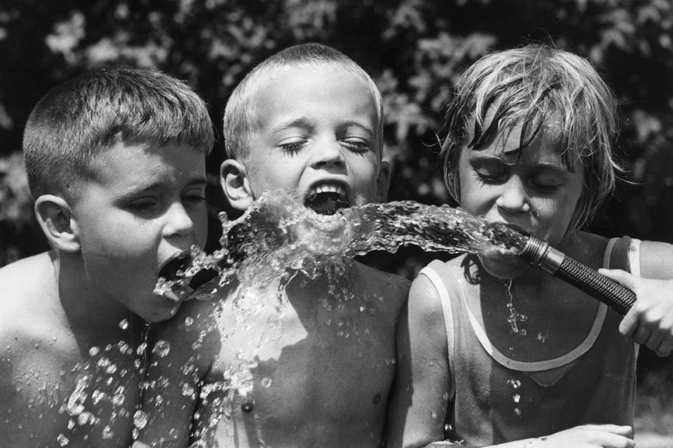 children drinking from garden hose