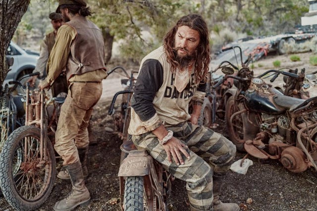 a person sitting on the ground next to a motorcycle