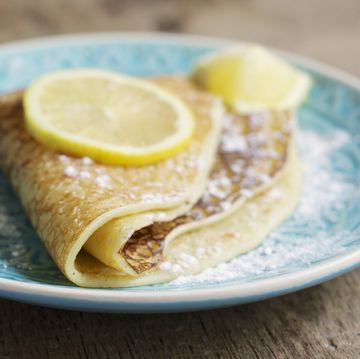 folded pancake topped with a slice of lemon on a blue plate