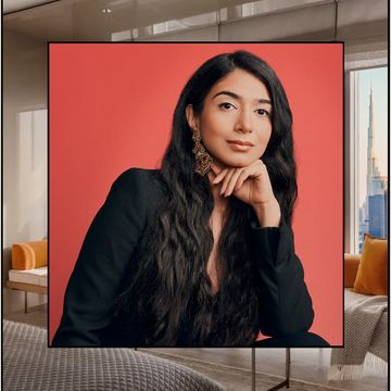 a luxurious hotel suite overlooking the dubai skyline, superimposed over is a portrait of shiza shahid